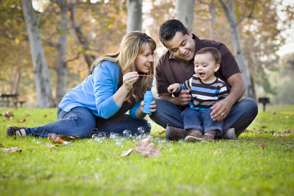 family sitting in park blowing bubbles